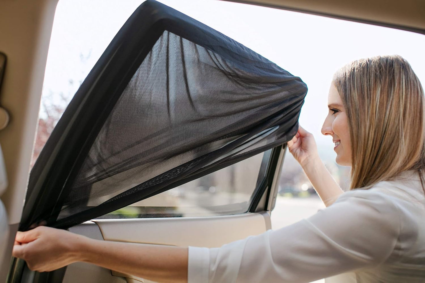Woman installing a car window sunshade in a vehicle