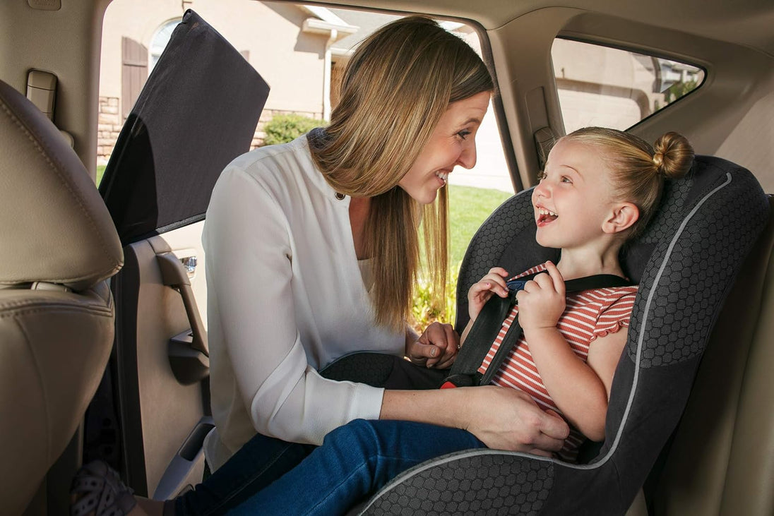 Woman adjusting a child's car seat in a vehicle, side window is covered with a sun shade