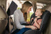 Woman adjusting a child's car seat in a vehicle, side window is covered with a sun shade